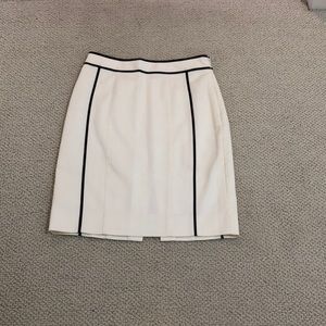 White, knee length skirt with black piping.
